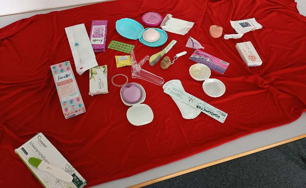 Auf einem Tisch liegen verschiedene Verhütungsmittel, Menstruationsprodukte und Schwangerschaftstests.