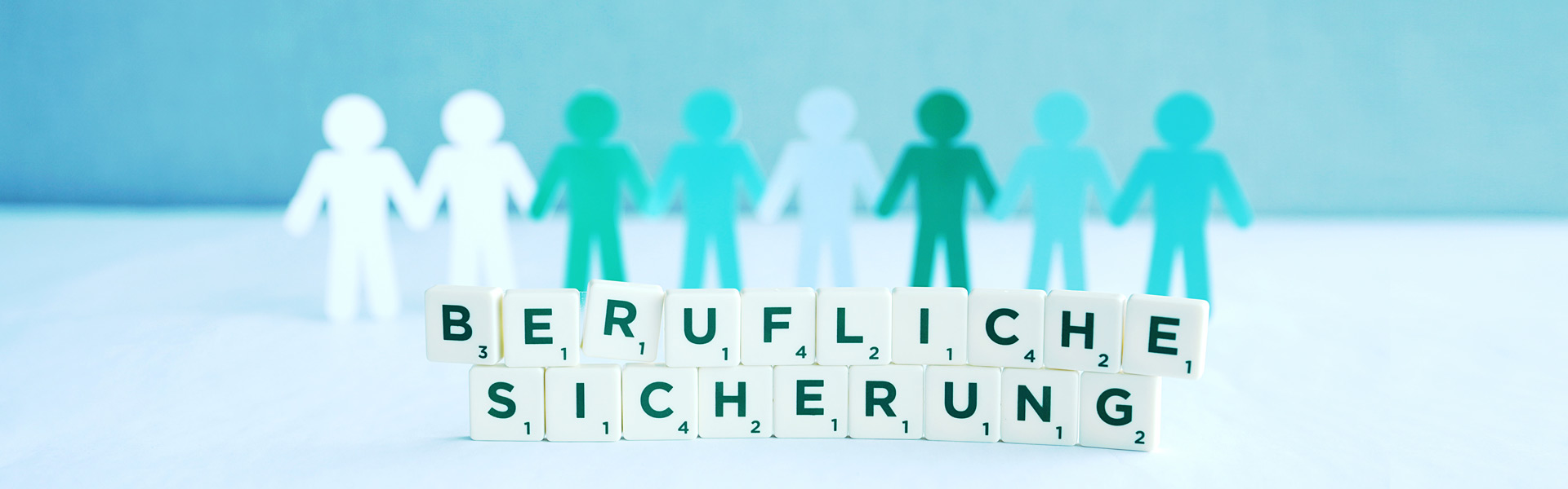 Im Hintergrund des Bild sind grüne Papiermännchen zu sehen, die sich an den Händen halten. Im Vordergrund steht in Buchstaben-Bausteinen "Berufliche Sicherung"